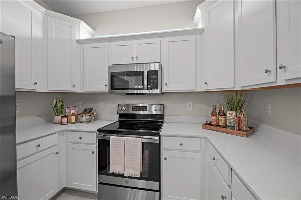 Kitchen with stainless steel appliances, light countertops, and white cabinetry