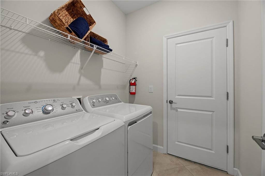 Laundry room with separate washer and dryer and light tile patterned flooring