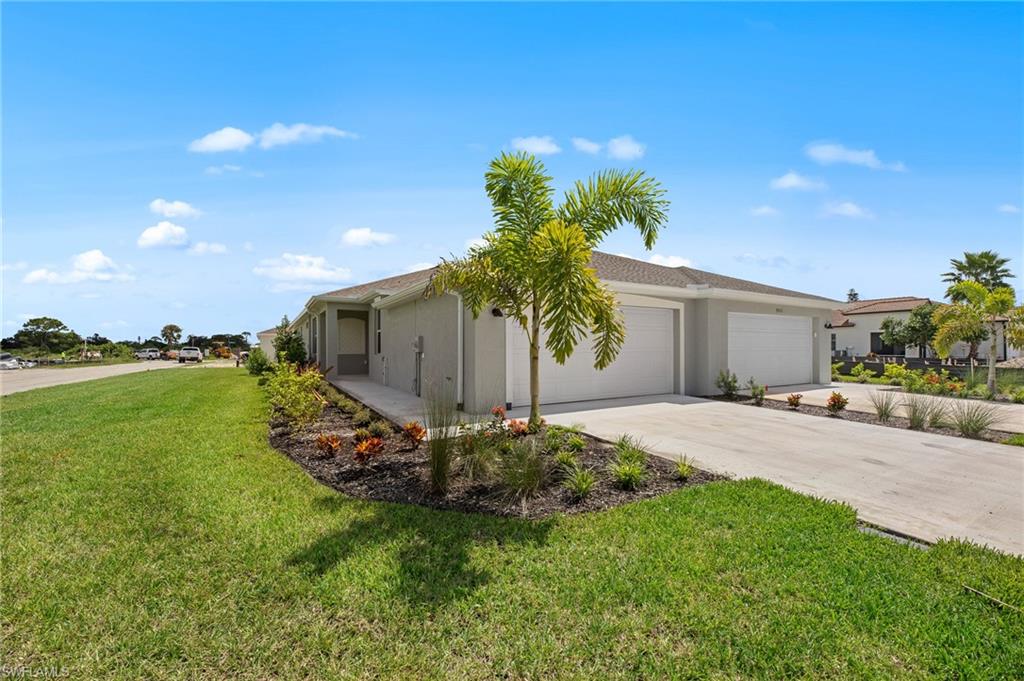 View of side of home with an attached garage, stucco siding, a yard, and driveway