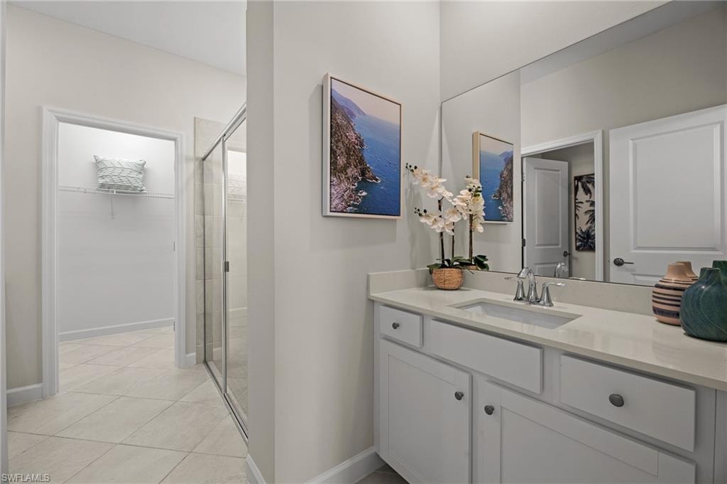 Full bathroom with a shower stall, vanity, tile patterned floors, and a spacious closet