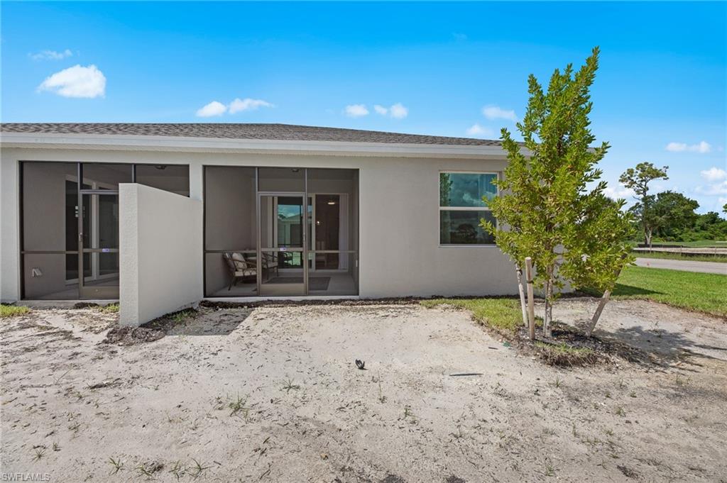 Rear view of property featuring a sunroom and stucco siding