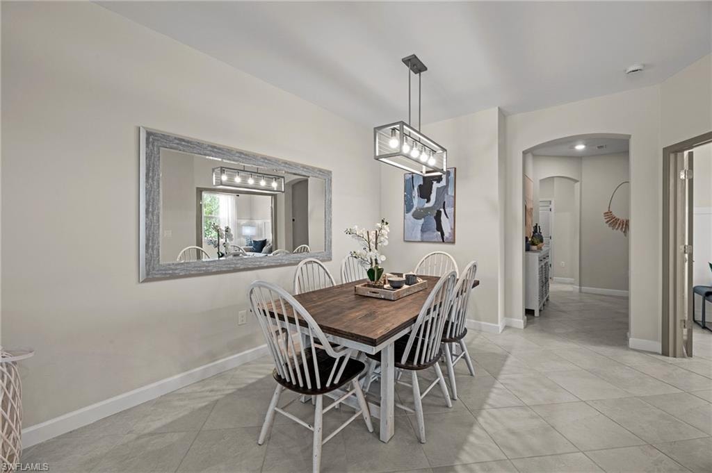 Dining room featuring arched walkways and light tile patterned floors