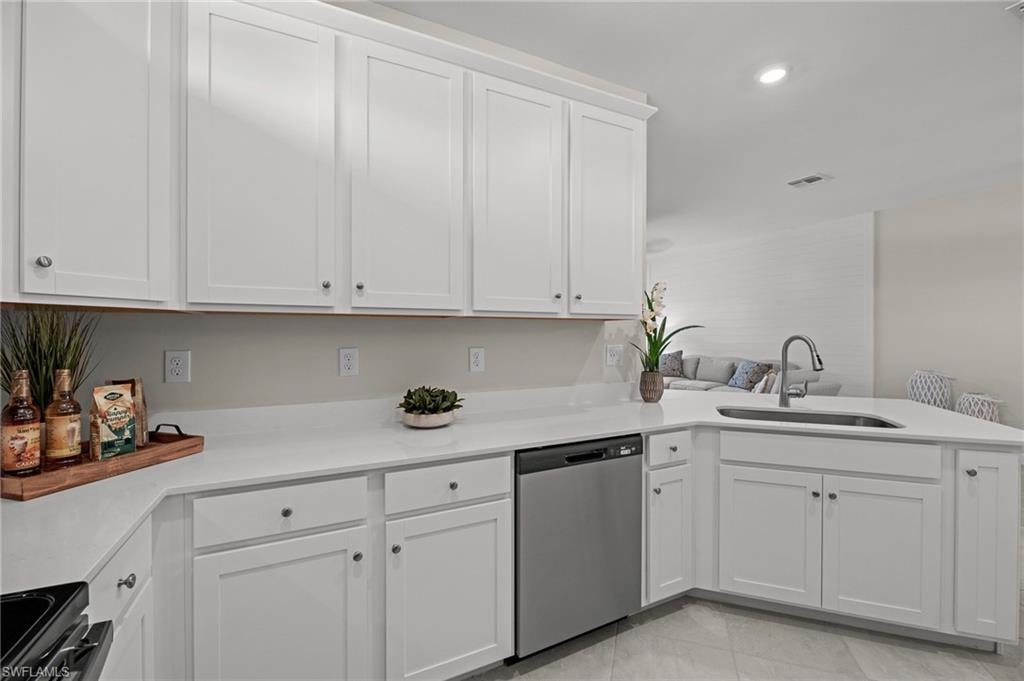 Kitchen with stainless steel dishwasher, a peninsula, light countertops, electric range, and white cabinets