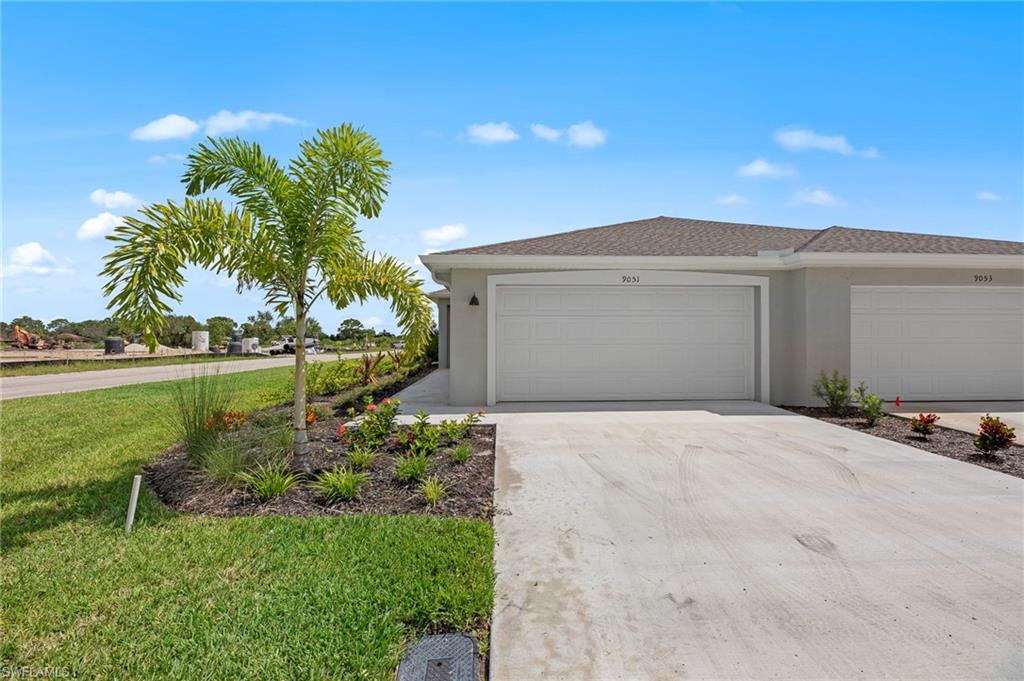 View of front of property featuring a garage, stucco siding, driveway, and a front lawn
