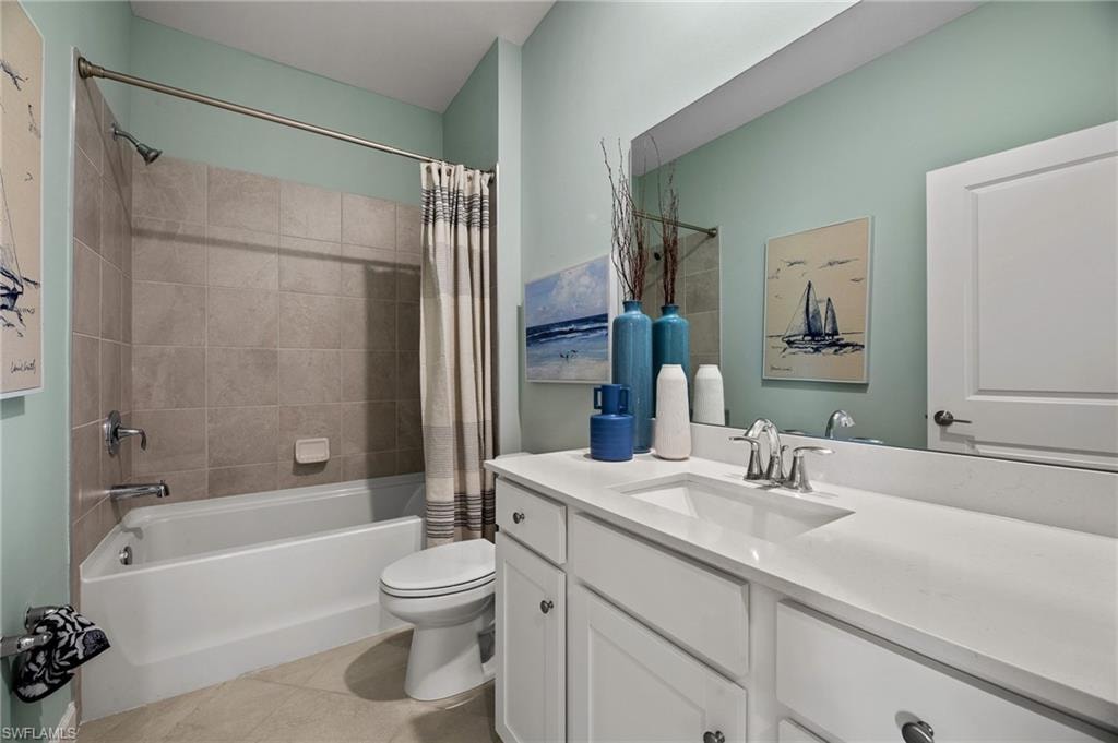 Bathroom with vanity, shower / bath combo with shower curtain, and tile patterned flooring