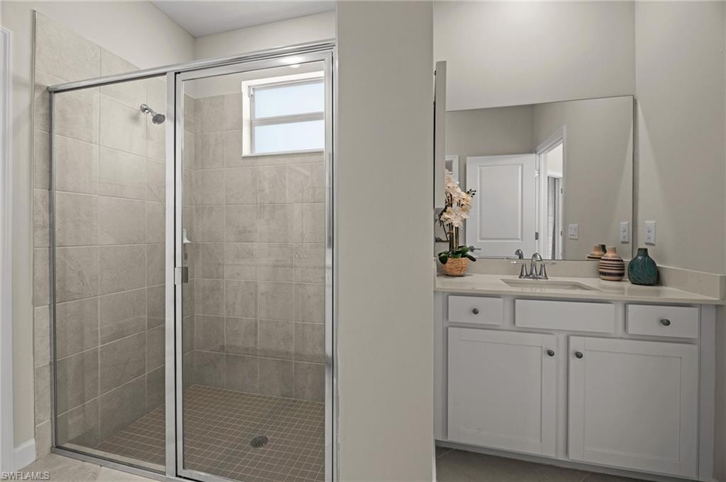 Bathroom with a shower stall, vanity, and tile patterned flooring