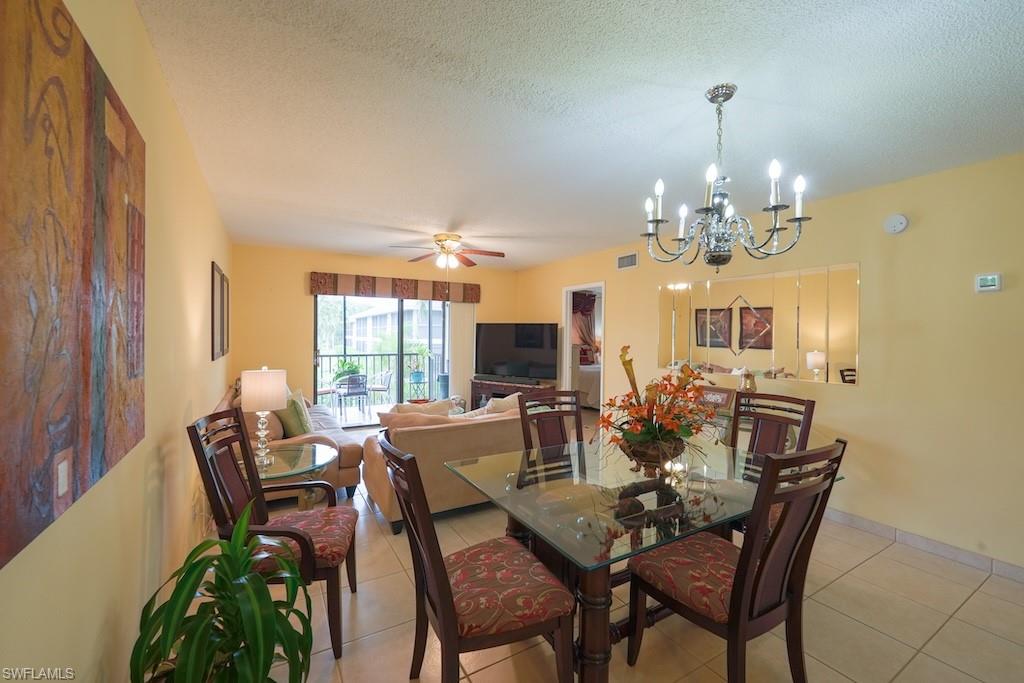 Dining area with light tile patterned floors, a chandelier, ceiling fan, and a textured ceiling