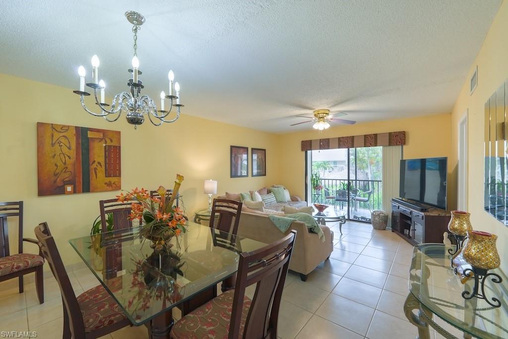 Dining space featuring a chandelier, light tile patterned flooring, a textured ceiling, and a ceiling fan