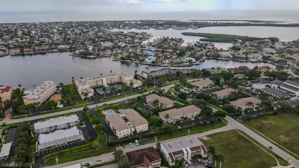 Aerial view of property and surrounding area featuring a nearby body of water and nearby suburban area