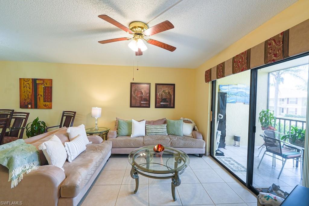 Living area featuring a ceiling fan, light tile patterned flooring, and a textured ceiling
