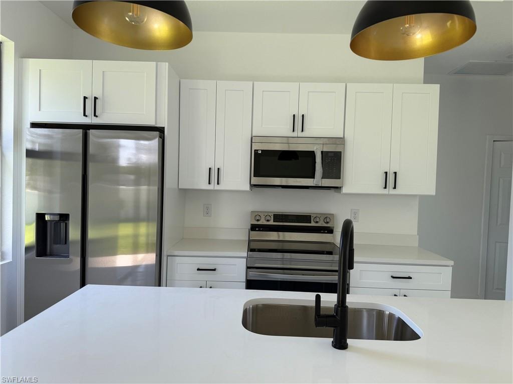 Kitchen with stainless steel appliances, light countertops, and white cabinets