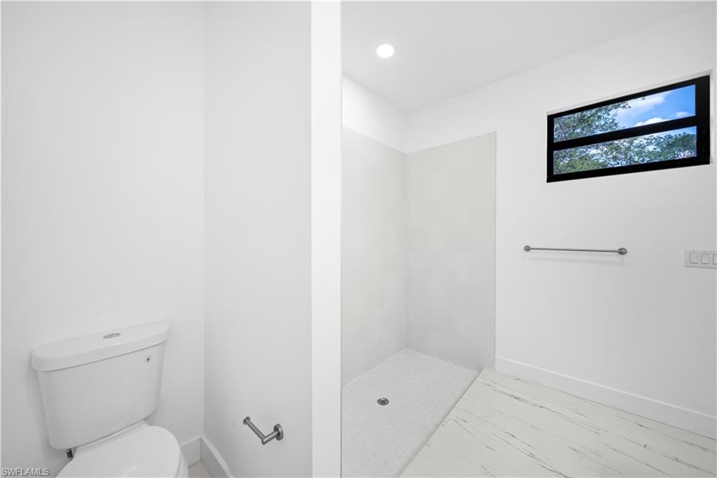 Walk-in shower with a mosaic tile floor and a window with a black frame