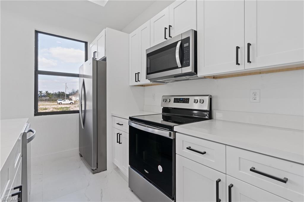 Kitchen with stainless steel appliances, light marble finish floors, light countertops, and white cabinets
