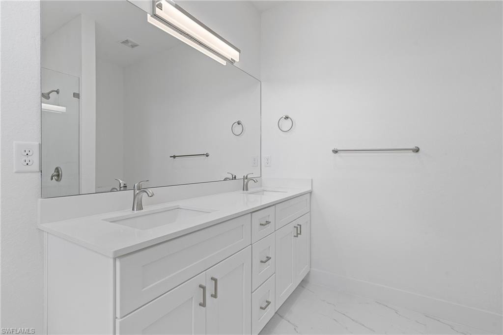Bathroom featuring marble look tiles and double vanity
