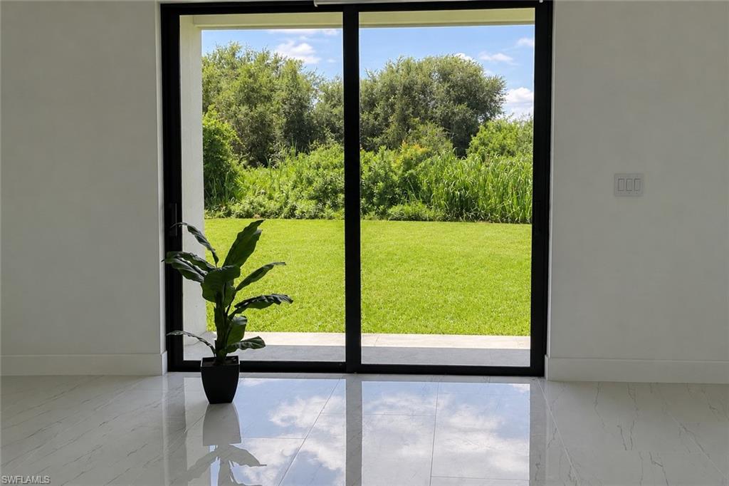 Sliding glass door, bright white walls, polished tile flooring, and expansive green lawn