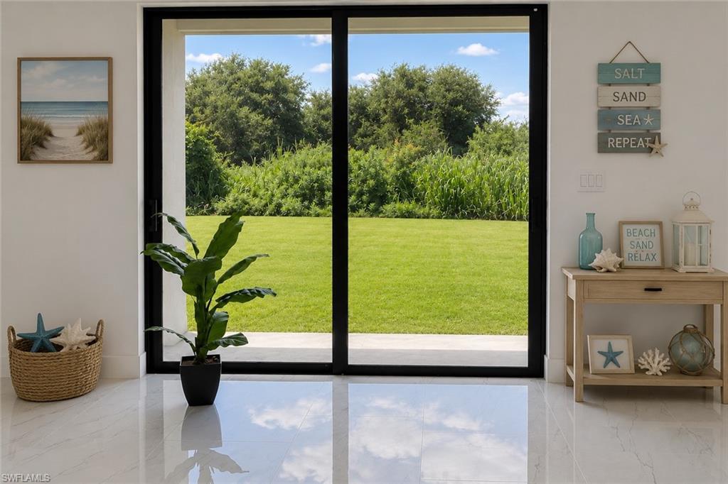 Polished tile flooring with a reflective finish, black-framed sliding glass doors, and a manicured lawn