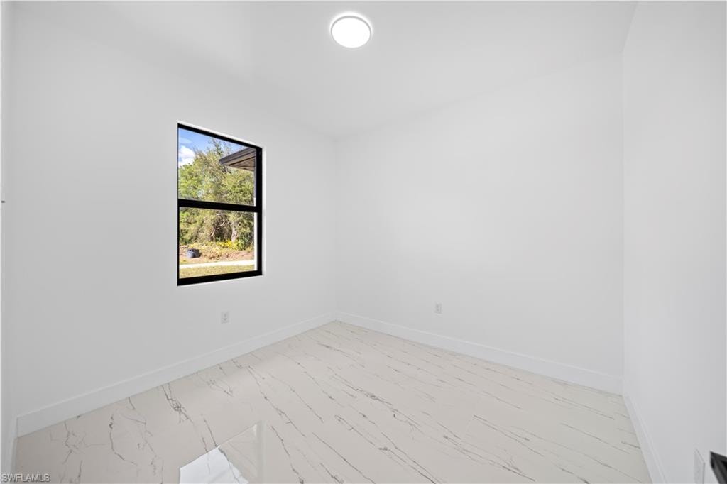 White walls, white baseboards, a black-framed window, and a flush mount ceiling light