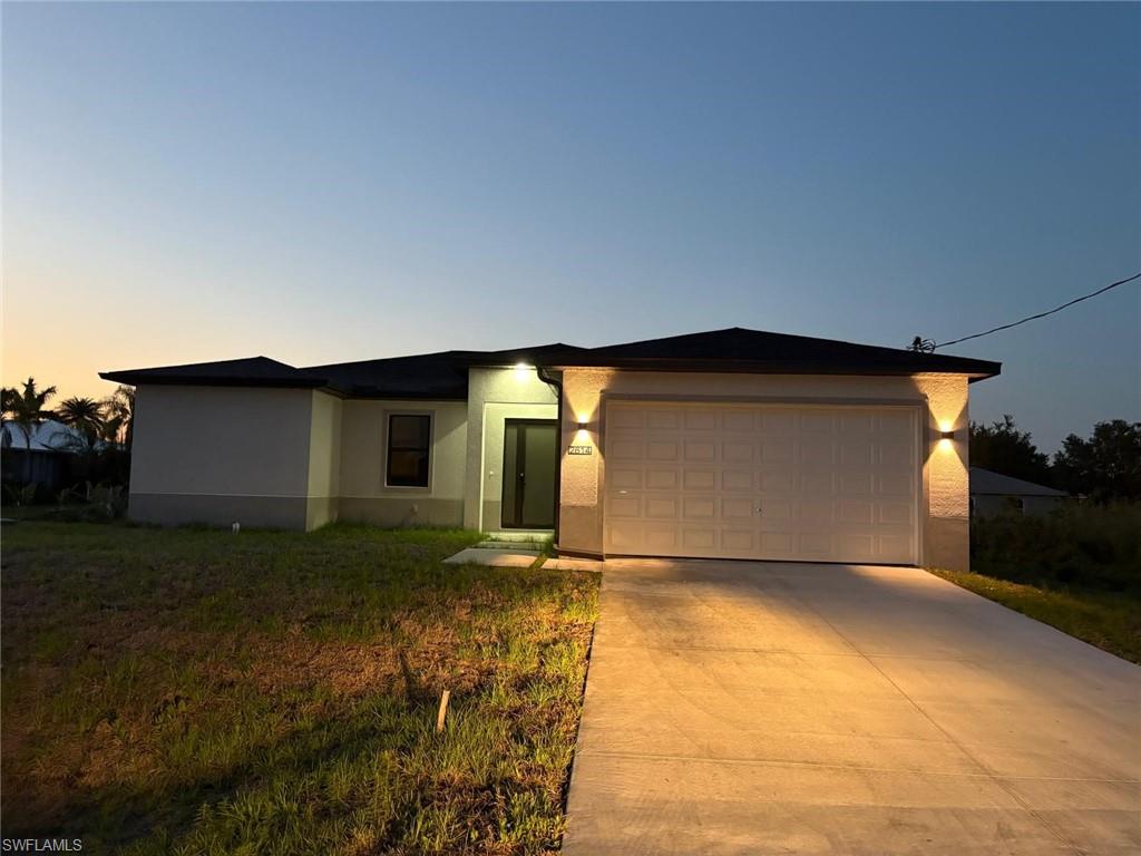 View of front facade with stucco siding, a garage, and concrete driveway