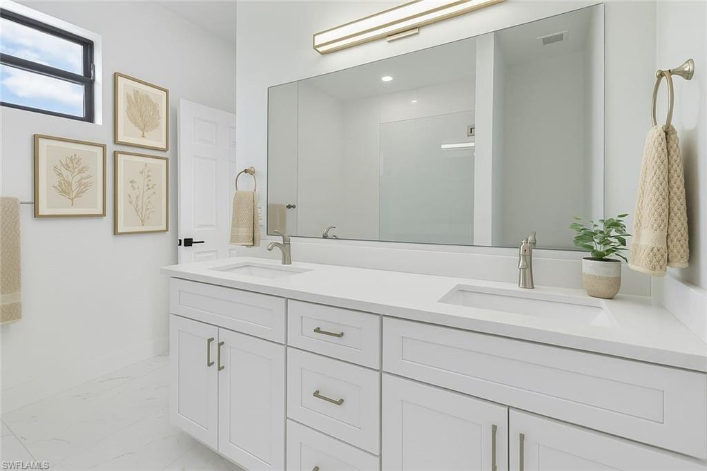 Bathroom with double vanity and marble finish flooring