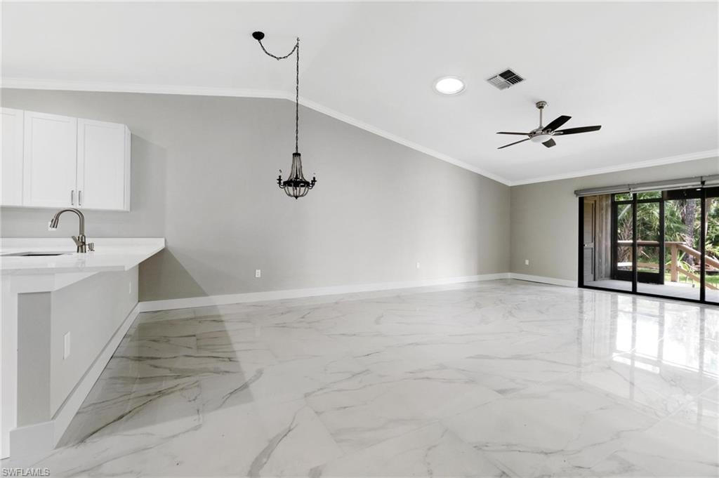 Unfurnished living room featuring light marble finish flooring, ceiling fan, crown molding, lofted ceiling, and recessed lighting