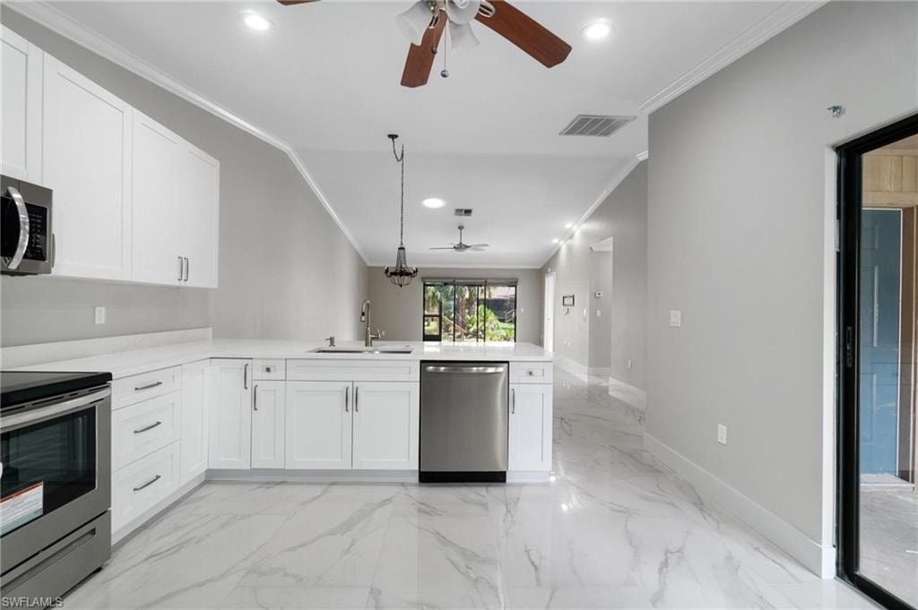Kitchen featuring appliances with stainless steel finishes, ceiling fan, crown molding, a peninsula, and white cabinets