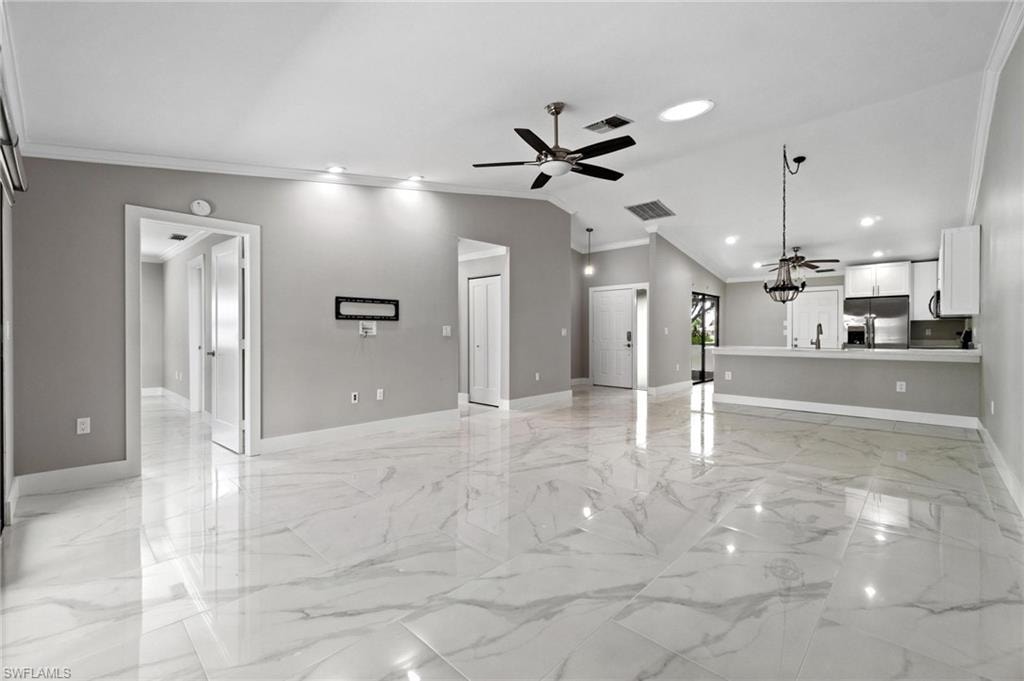 Unfurnished living room featuring a ceiling fan, light marble finish flooring, crown molding, recessed lighting, and lofted ceiling