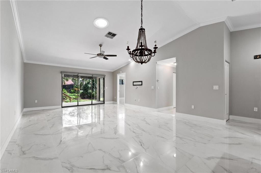 Empty room with crown molding, ceiling fan, light marble finish flooring, a chandelier, and lofted ceiling