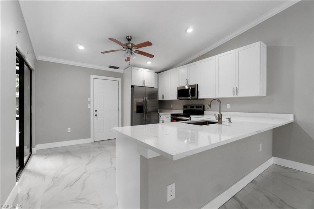 Kitchen featuring stainless steel appliances, light marble finish flooring, ceiling fan, a peninsula, and white cabinetry