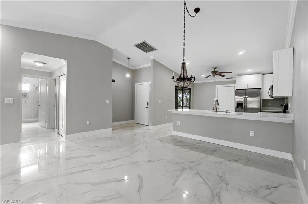 Unfurnished living room with ornamental molding, light marble finish flooring, a ceiling fan, recessed lighting, and lofted ceiling