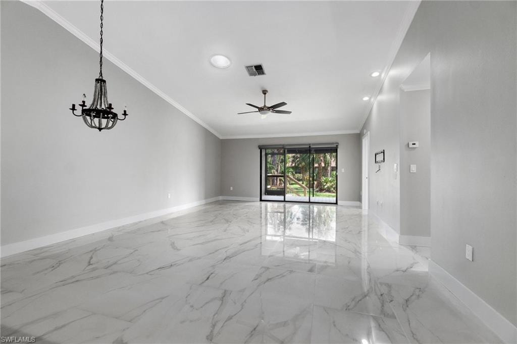 Empty room featuring crown molding, a ceiling fan, light marble finish floors, a chandelier, and recessed lighting