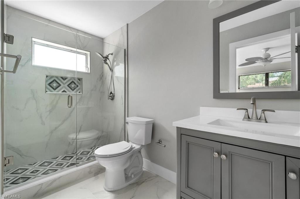 Bathroom with vanity, a marble finish shower, marble finish floors, and ceiling fan