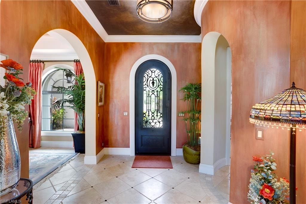Entryway with Custom Wrought Iron Door, faux painted walls and ceiling, ornamental molding and stone travertine floor