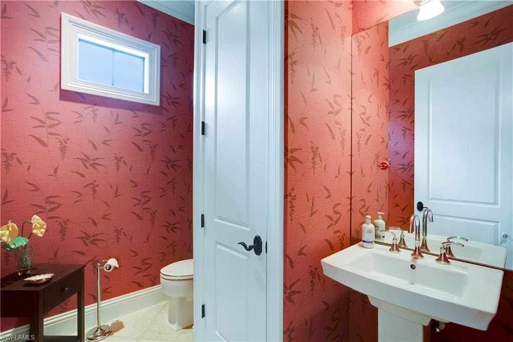 Half bathroom with a sink and wallpapered walls