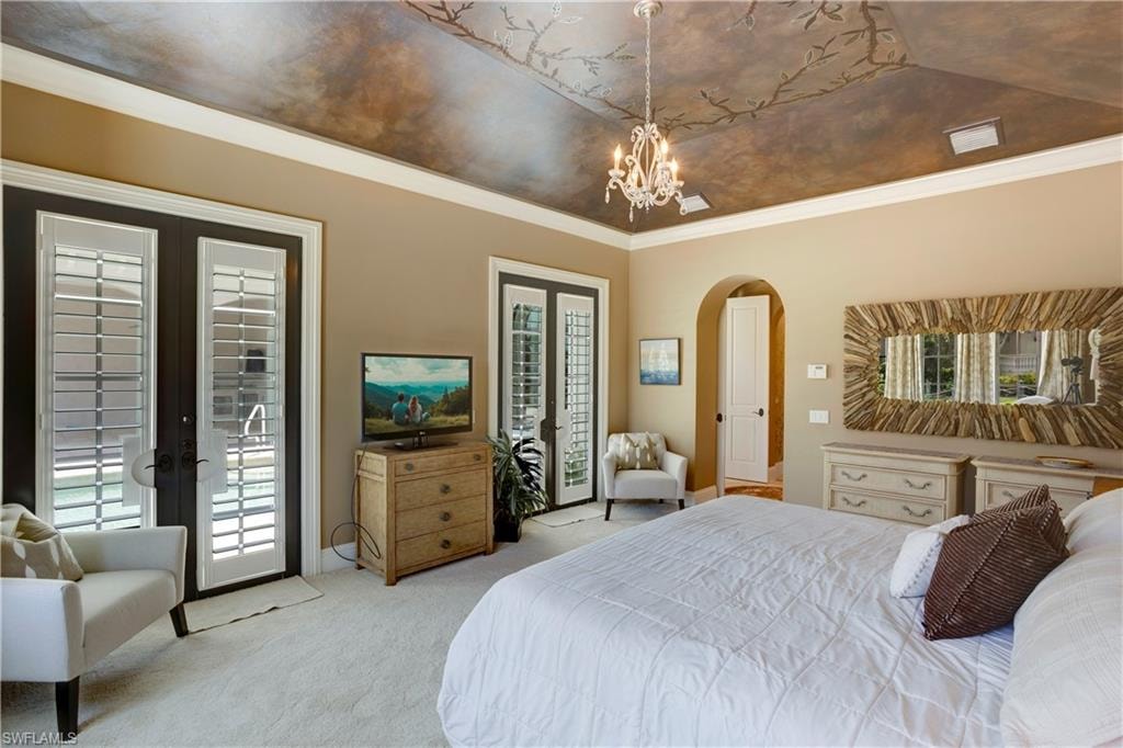 Bedroom featuring french doors, light carpet, arched walkways, access to outside, and a chandelier