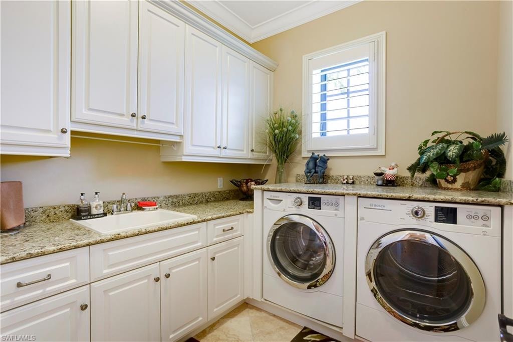 Large laundry room with separate washer and dryer, lots of cabinet space, and crown molding