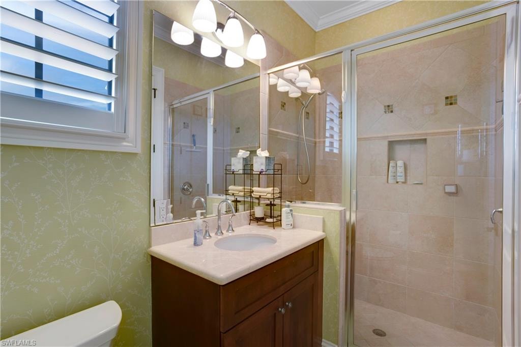 Bathroom with vanity, a shower stall, and wallpapered walls