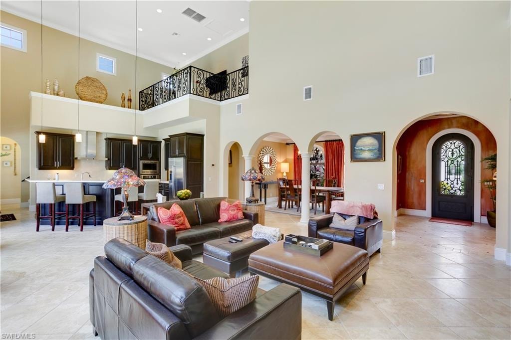 Living room featuring 22 ft ceilings, arched walkways, and plenty of natural light, ornamental molding, and light tile patterned floors