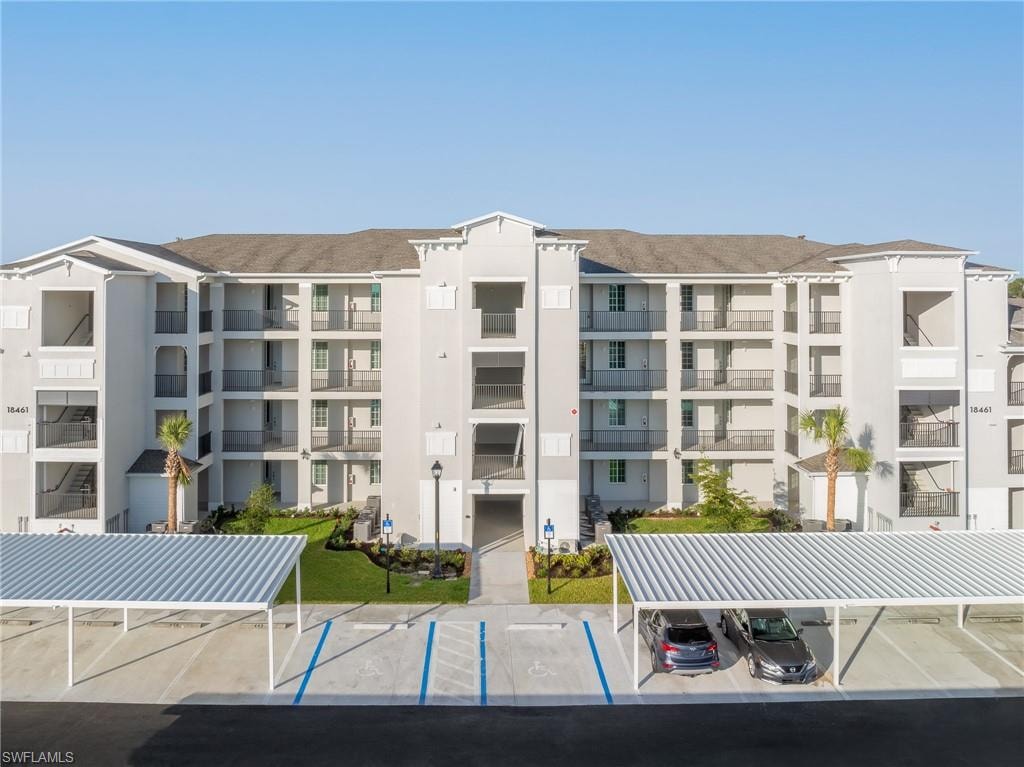 View of apartment building / complex featuring covered parking