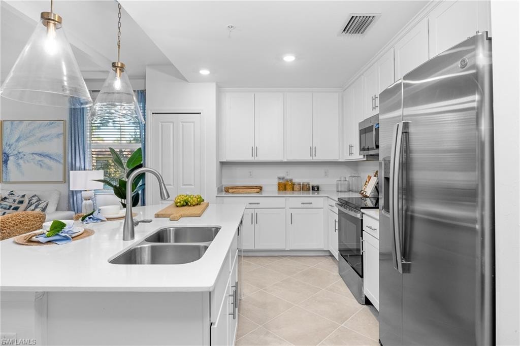 Kitchen featuring stainless steel appliances, light countertops, white cabinetry, light tile patterned floors, and recessed lighting