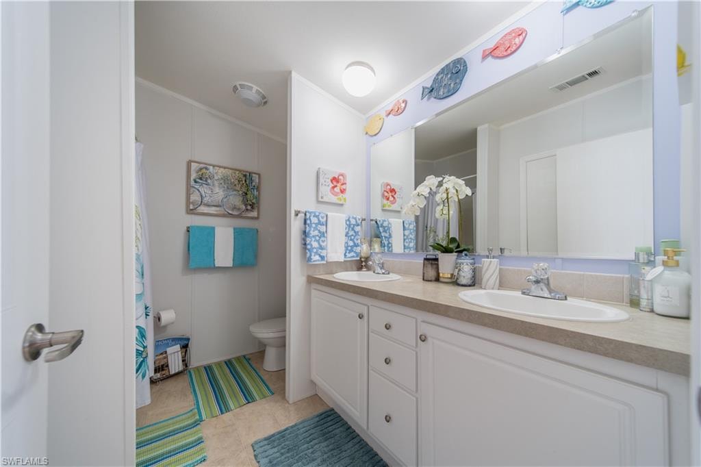 Full bathroom featuring double vanity, ornamental molding, and curtained shower
