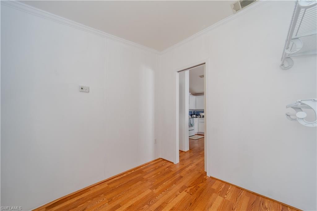 Unfurnished room featuring light wood-style floors and crown molding