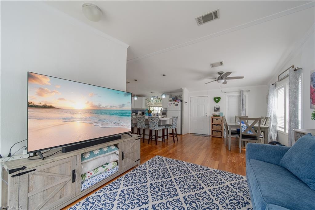 Living area featuring wood finished floors, ceiling fan, and ornamental molding