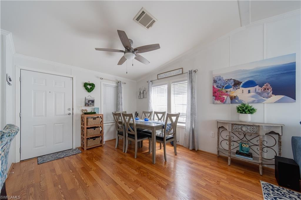 Dining room featuring ornamental molding, light wood finished floors, ceiling fan, and vaulted ceiling