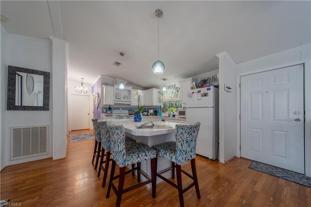 Dining area featuring wood finished floors, lofted ceiling, ornamental molding, and a chandelier