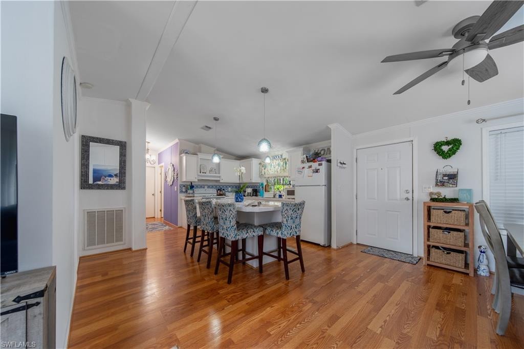 Dining room featuring light wood-style flooring, a ceiling fan, and crown molding