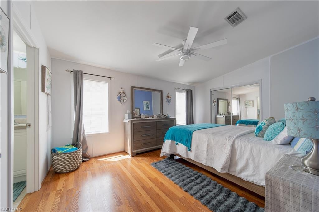 Bedroom featuring multiple windows, lofted ceiling, light wood finished floors, a closet, and ceiling fan