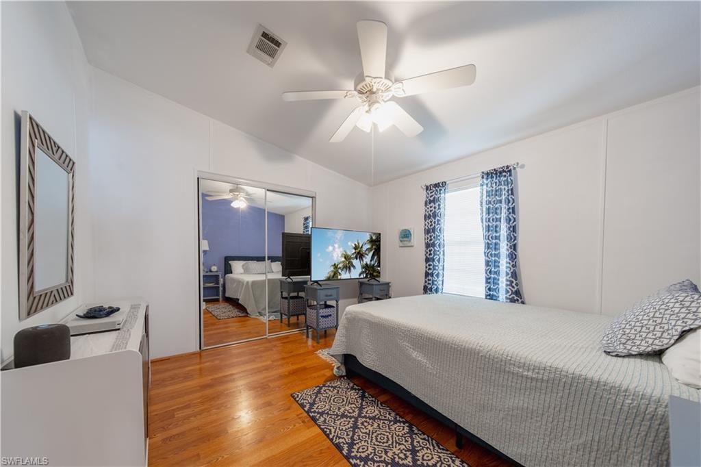 Bedroom with vaulted ceiling, wood finished floors, ceiling fan, and a closet