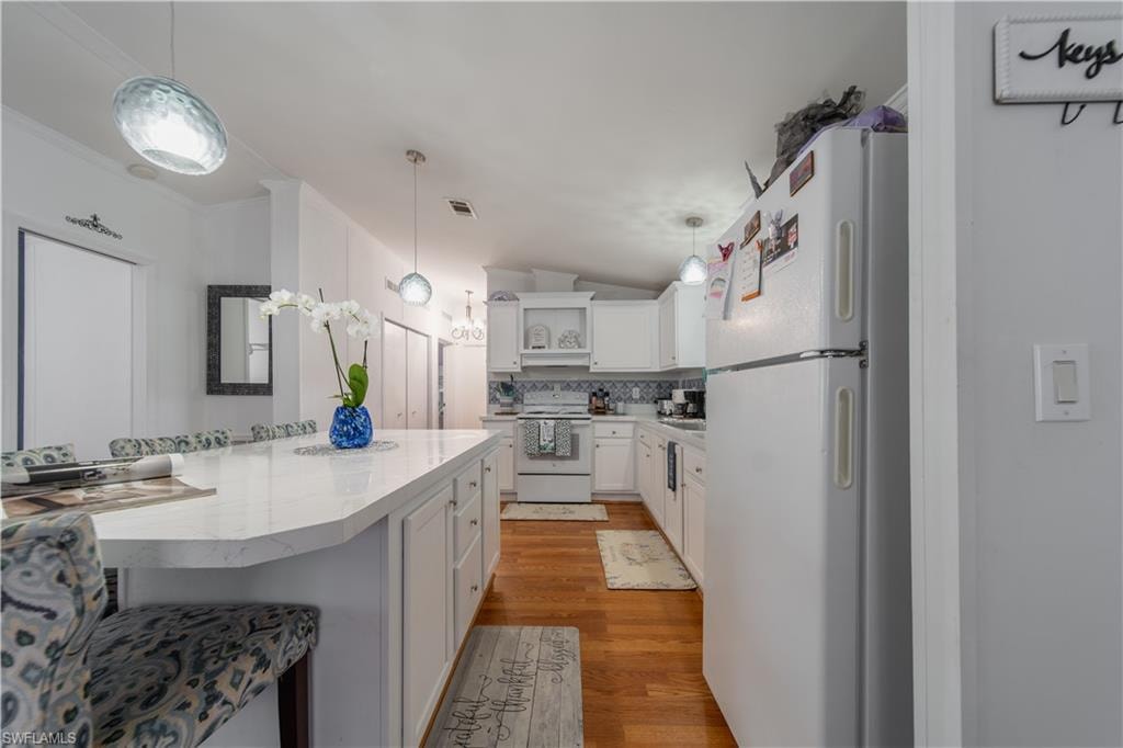 Kitchen featuring white appliances, open shelves, white cabinetry, light wood finished floors, and pendant lighting