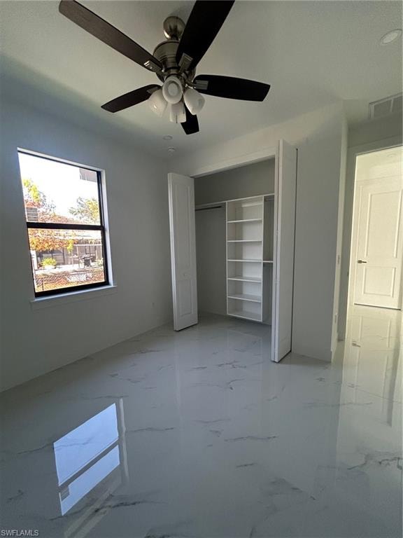 Unfurnished bedroom with marble tiled floors, a ceiling fan, and a closet