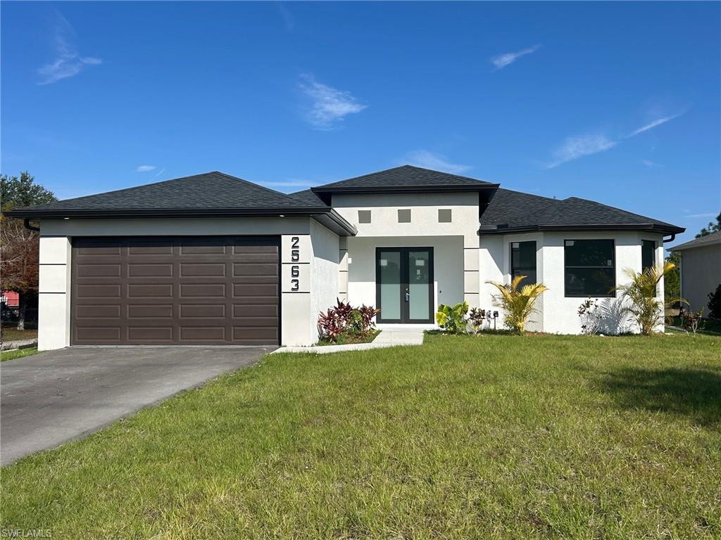 Prairie-style home featuring stucco siding, a front lawn, driveway, roof with shingles, and an attached garage